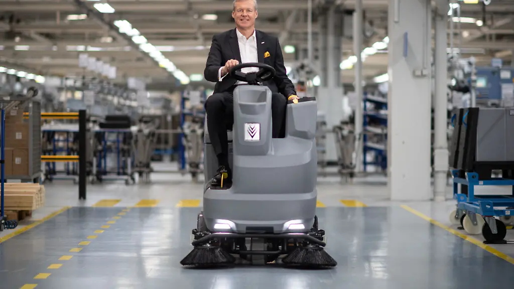 Hartmut-Jenner-Vorsitzender-des-Vorstands-der-Alfred-Kaercher-SE-Co-KG-faehrt-in-einer-Werkshalle-auf-einer-Scheuersaugmaschine