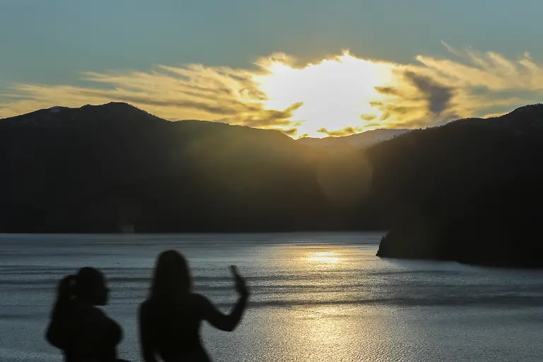 People-take-photos-by-Lake-Lacar-before-sunset-outside-San-Martin-de-los-Andes-Northwest-Patagonia-s-Neuquen-province-Argentina-05-July-2025-L-car-Lake-is-a-lake-of-glacial-origin-located-within-Lan-n-National-Park-in-Neuqu-n-Province-Argentina-near-the-city-of-San-Mart-n-de-los-Andes-It-is-enclosed-in-the-Andes-mountain-range-at-630-m-above-sea-level-surrounded-by-a-mountainous-region-ranging-1-600-to-1-900-m-Lago-L-car-features-several-beaches-and-is-bordered-by-the-alpine-style-town-of-San-Mart-n-de-los-Andes-which-is-a-popular-starting-point-for-exploring-the-surrounding-lakes