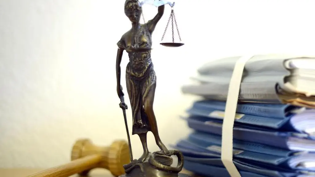 Eine-modellhafte-Nachbildung-der-Justitia-steht-neben-einem-Holzhammer-und-einem-Aktenstapel