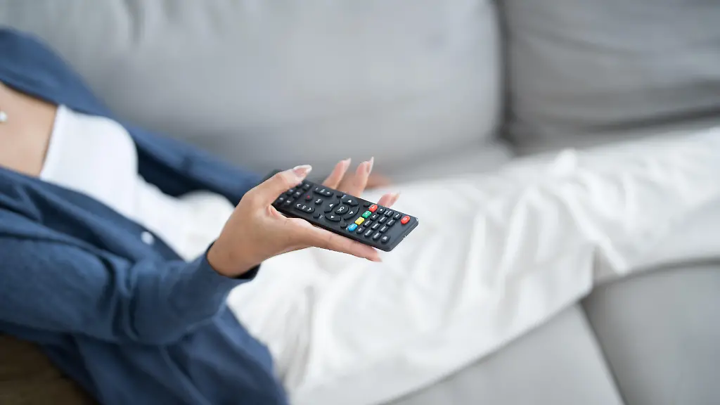 Asian-woman-Watching-smart-TV-and-using-remote-controller-Hand-holding-television-audio-remote-control-at-home-with-the-remote-control-television
