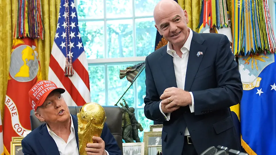 FILE-President-Donald-Trump-holds-the-FIFA-World-Cup-Winners-Trophy-as-FIFA-President-Gianni-Infantino-looks-on-during-an-announcement-in-the-Oval-Office-of-the-White-House-Aug-22-2025-in-Washington