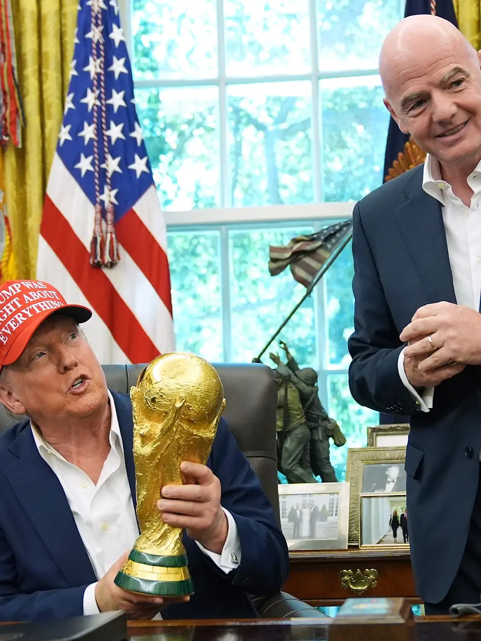 FILE-President-Donald-Trump-holds-the-FIFA-World-Cup-Winners-Trophy-as-FIFA-President-Gianni-Infantino-looks-on-during-an-announcement-in-the-Oval-Office-of-the-White-House-Aug-22-2025-in-Washington