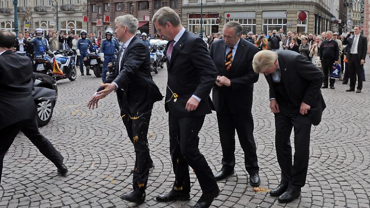 Platsch: Ein Bodyguard hält schützend seine Hand vor Wulff. Der musste sich erst einmal umziehen.