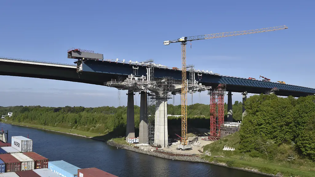 Containerschiff-faehrt-im-Nord-Ostsee-Kanal-an-der-Baustelle-der-Rader-Hochbruecke-vorbei-NOK-Kielkanal-Kielcanal-Schleswig-Holstein-Deutschland