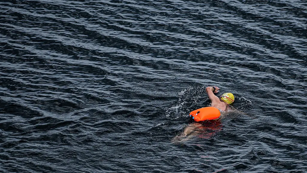 Leuchtend-orange-pink-oder-gelb-zieht-sie-hinter-Schwimmern-durchs-Wasser-die-Schwimmboje-befestigt-ueber-einen-Guertel