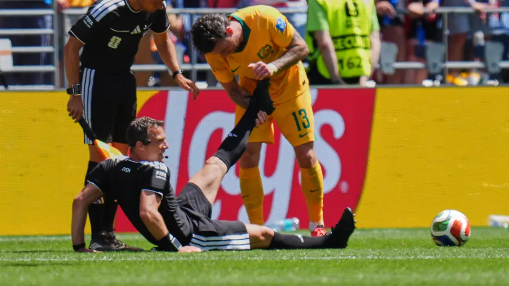 Fussball-Maenner-WM-2026-USA-Australien-Vorrunde-Gruppe-D-Spieltag-2-Seattle-Stadion-Schiedsrichter-Felix-Zwayer-Deutschland-sitzt-auf-dem-Rasen-bekommt-vom-Australier-Aiden-O-Neill-Unterstuetzung