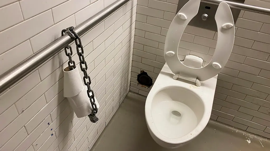 New-York-NY-USA-May-28-2021-Toilet-paper-chained-to-steel-bar-in-public-restroom-to-prevent-theft-of-the-entire-roll-of-toilet-paper