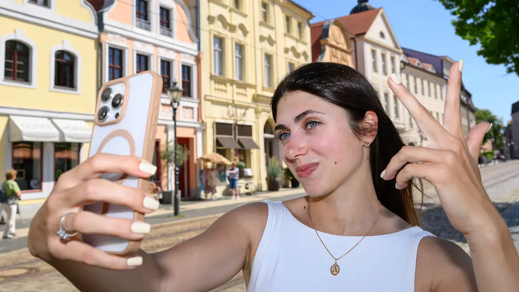 Diana-Yukhimets-Ukrainerin-und-Influencerin-nimmt-auf-dem-Altmarkt-von-Cottbus-eine-Video-von-sich-auf-Als-Diana-Yukhimets-vor-vier-Jahren-nach-Cottbus-kam-war-sie-wenig-begeistert-Ihr-erster-Eindruck-Grau-schrecklich-sagt-sie-heute-und-lacht-Die-Ukrainerin-war-nach-ihrer-Flucht-zunaechst-im-Stadtteil-Schmellwitz-untergebracht-Kiew-ist-bunt-gross-und-schoen-Millionenstadt-Und-dann-Cottbus-Das-war-eine-Katastrophe-Heute-gehoert-ausgerechnet-sie-zu-den-sichtbarsten-Botschafterinnen-der-Lausitzmetropole-Mit-ihrem-Instagram-Kanal-cottbus-heute-erreicht-die-29-Jaehrige-Tausende-Menschen-einzelne-Videos-werden-Hunderttausendfach-angesehen
