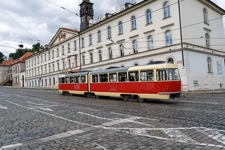 Eine-Oldtimer-Rot-und-Rahmbahn-faehrt-entlang-einer-Steinstrasse-in-Prag-Tschechien-in-der-Naehe-der-beruehmten-Prager-Burg-Dieses-Bild-erfasst-den-historischen-Charme-der-Stadt-und-den-einzigartigen-Transport