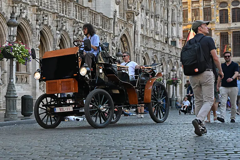 Eine-E-Kutsche-faehrt-ueber-den-Grand-Place-Grote-Markt-im-Zentrum-von-Bruessel-Nach-anhaltender-Kritik-an-der-Nutzung-von-Pferden-fuer-touristische-Zwecke-fuehrte-die-belgische-Hauptstadt-2024-elektrische-Kutschen-ein-Die-bei-Touristen-beliebte-Millionenstadt-galt-mit-dem-Projekt-als-Vorreiter