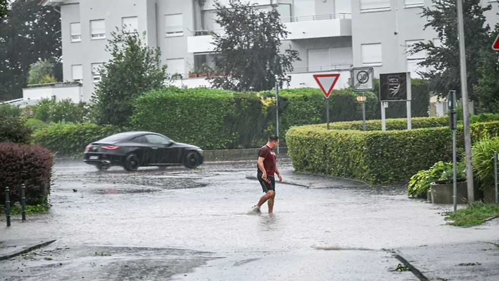 Ein-Mann-laeuft-in-Friedrichshafen-am-Bodensee-durch-eine-tiefe-Pfuetze