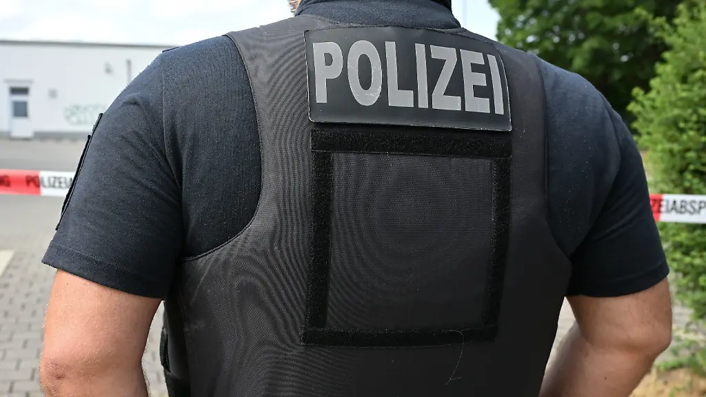 15-07-2026-Sachsen-Dresden-Ein-Polizist-in-Schutzweste-steht-vor-einem-Absperrband-im-Einsatzbereich-an-einem-Supermarkt-Die-Dresdner-Polizei-hat-am-Morgen-einen-bewaffneten-Mann-ueberwaeltigt