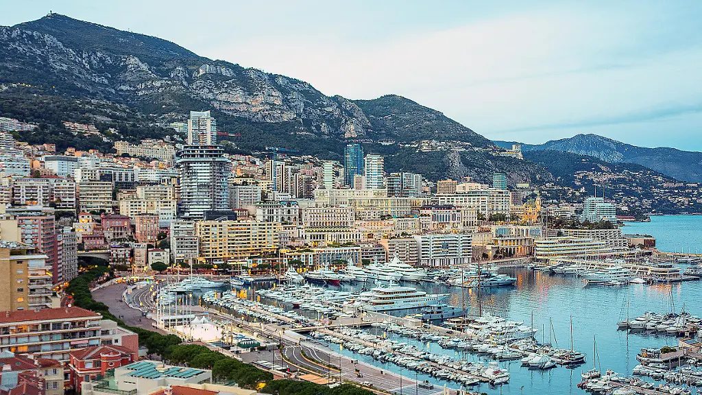 Elevated-view-of-Port-Hercule-filled-with-yachts-and-luxury-boats-in-Monaco-on-February-15-2026-The-Monte-Carlo-waterfront-city-buildings-and-surrounding-mountains-are-visible-at-dusk-along-the-Mediterranean-coast-Vue-en-hauteur-du-Port-Hercule-avec-des-yachts-et-bateaux-de-luxe-a-Monaco-le-15-Fevrier-2026-Le-front-de-mer-de-Monte-Carlo-les-immeubles-de-la-ville-et-les-montagnes-environnantes-sont-visibles-au-crepuscule-le-long-de-la-cote-mediterraneenne