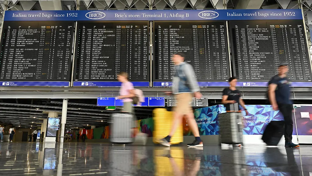 09-07-2026-Hessen-Frankfurt-am-Main-Urlauber-laufen-im-Terminal-1-an-einer-grossen-Anzeigetafel-vorbei-Allein-2025-waren-rund-63-2-Millionen-Fluggaeste-am-Frankfurter-Flughafen