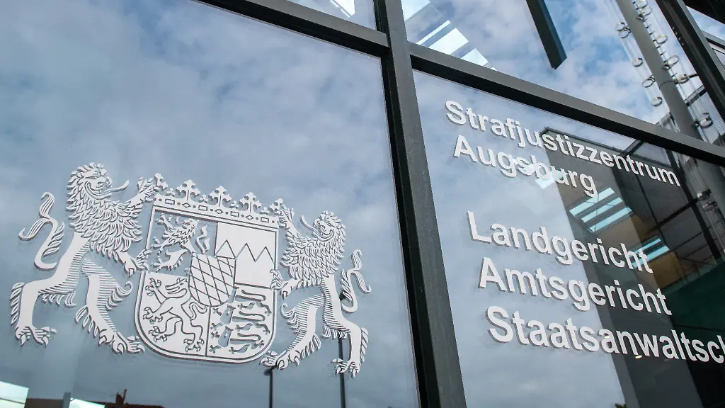 Am-Strafjustizzentrum-Augsburg-prangt-das-bayerische-Staatswappen-In-dem-Justizzentrum-muessen-sich-drei-Maenner-wegen-versuchten-Mordes-verantworten-Sie-sollen-im-Dezember-2021-ein-aelteres-Ehepaar-in-ihrem-Schlafzimmer-ueberfallen-und-schwer-verletzt-haben