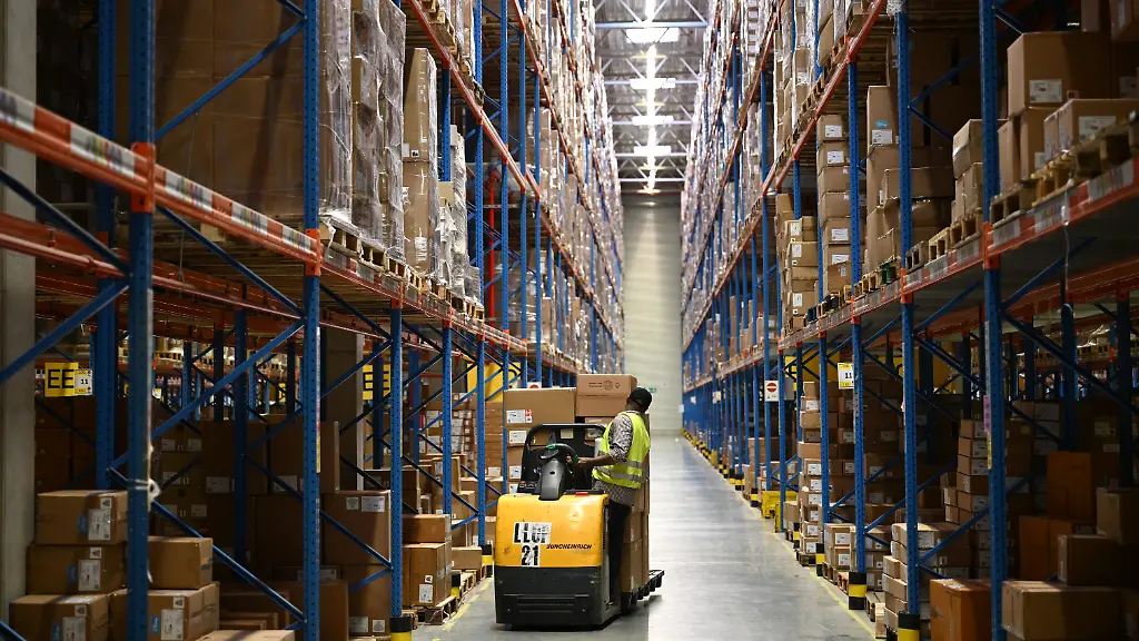 Ein-Mitarbeiter-von-DHL-steht-in-einem-Hochregallager-des-Konzernbereichs-Supply-Chain-Lieferketten-auf-einem-Gabelstapler-der-Firma-Jungheinrich-und-blickt-auf-eine-Regalwand-DHL-ist-einer-der-groessten-Logistiker-der-Welt-in-dem-Hochregallager-lagert-das-Unternehmen-Ware-fuer-eine-Modekette-aus-dem-Lager-werden-Filialen-der-Kette-in-grossen-Teilen-Westdeutschland-sowie-in-den-Niederlanden-und-Belgien-beliefert
