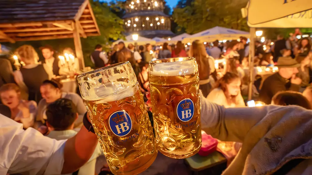 Deutschland-Muenchen-19-Juli-2026-Biertrinken-bei-Kerzenschein-traditioneller-Kocherlball-am-Chinesischen-Turm-Englischer-Garten-zwei-Besucher-stossen-mit-ihren-Masskruegen-an-4-45-Uhr-in-der-frueh-manche-Besucher-sind-schon-um-3-Uhr-frueh-im-Biergarten-um-noch-einen-Platz-zu-ergattern-die-Menschen-trinken-ein-Bier-essen-eine-Brotzeit-tragen-Tracht-Tradition-entstand-im-19-Jahrhundert-als-Hauspersonal-Dienstboten-und-KoechInnen-in-den-fruehen-Morgenstunden-vor-Dienstbeginn-gefeiert-und-getanzt-haben-Tradition-wurde-ab-1989-wiederbelebt-traditionell-am-3