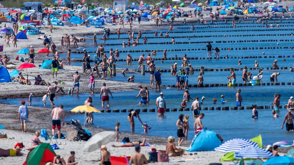 Im-und-am-Wasser-der-Ostsee-suchen-Urlauber-und-Tagesgaeste-am-Warnemuender-Strand-etwas-Abkuehlung-am-bisher-heissesten-Tag-in-Deutschland-Mit-Temperaturen-bis-zu-36-Grad-und-wolkenfreiem-Himmel-zeigt-sich-der-Sommer-in-Norddeutschland