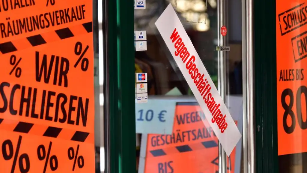 wegen-Geschaeftsaufgabe-steht-auf-dem-Aufkleber-an-der-Tuer-eines-Geschaefts-in-der-Innenstadt