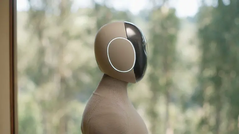 VIDEO-AVAILABLE-CONTACT-INFO-COVERMG-COM-TO-RECEIVE-A-humanoid-A-I-powered-home-help-robot-is-set-to-be-tested-in-homes-Norway-and-Silicon-Valley-based-robotics-firm-1X-has-unveiled-its-latest-humanoid-robot-Neo-Gamma-It-is-designed-to-assist-with-household-chores-while-blending-seamlessly-into-domestic-settings-Wrapped-in-a-beige-3D-knitted-bodysuit-the-robot-aims-to-fit-into-homes-with-its-minimalist-appearance-Neo-Gamma-boasts-a-more-Scandinavian-inspired-design-and-is-equipped-to-perform-tasks-such-as-vacuuming-tidying-and-doing-the-laundry-The-robots-integrated-artificial-intelligence-system-enables-it-to-approximate-human-speech-and-body-language-enhancing-its-ability-to-interact-with-users-Neo-Gamma-s-humanoid-frame-includes-advanced-audio-and-communication-features-It-has-four-microphones-for-audio-capture-and-a-speaker-system-with-one-speaker-in-the-chest-for-AI-voice-interaction-and-two-in-the-pelvis-for-bass-sound-effects-and-music-To-improve-communication-1X-has-added-emotive-ear-rings-on-the-sides-of-the-robot-s-head-which-light-up-to-indicate-when-it-is-speaking-or-listening-The-robot-has-been-trained-using-human-motion-capture-data-allowing-it-to-walk-with-a-natural-gait-swing-its-arms-squat-and-sit-in-chairs-Images-released-by-1X-show-Neo-Gamma-performing-everyday-household-tasks-such-as-preparing-coffee-and-vacuuming-floors-Its-multi-jointed-hands-which-mimic-human-tendon-movement-are-controlled-by-elastic-motors-and-encased-in-soft-covers-for-additional-safety-While-the-Neo-Gamma-is-still-a-prototype-the-company-plans-to-begin-limited-in-home-testing-The-soft-knitted-nylon-covering-serves-both-aesthetic-and-practical-purposes-It-reduces-potential-injuries-from-robot-to-human-contact-and-helps-lower-the-robot-s-operating-noise-to-about-the-same-level-as-a-refrigerator-according-to-1X-A-significant-factor-in-Neo-Gammas-advanced-capabilities-lies-in-the-firms-partnership-with-OpenAI
