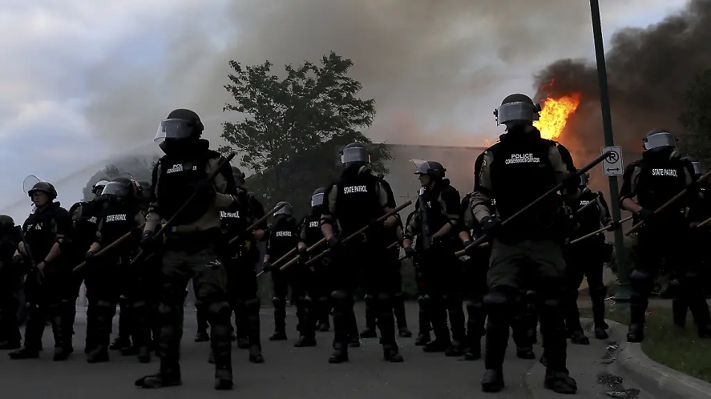 In-Minneapolis-versammeln-sich-Polizisten-in-Schutzausruestung-vor-einem-brennenden-Gebaeude