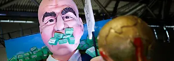 FIFA-Praesident-Gianni-Infantino-mit-Geldbuendeln-im-Mund-beim-Richtfest-der-Persiflagewagen-und-Karnevalswagen-zum-Koelner-Rosenmontagszug-2023-in-der-Koelnmesse-Der-Jubilaeumszoch-startet-anlaesslich-200-Jahre-Koelner-Karneval-auf-der-rechten-Rheinseite-und-soll-beide-Rheinseiten-miteinander-verbinden-Koeln-14-02