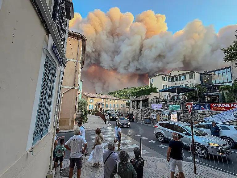 COTIGNAC-FRANCE-JULY-21-Bystanders-watch-the-smoke-and-flames-from-a-wildfire-on-July-21-2026-in-Cotignac-France-Over-1-000-firefighters-were-called-in-to-control-the-fast-moving-wildfire-that-has-burned-more-than-2-500-hectares-in-southern-France