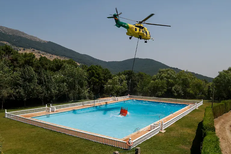 CASILLAS-SPAIN-JULY-28-A-helicopter-collects-water-from-a-swimming-pool-to-combat-wildfires-on-July-28-2026-in-Casillas-in-Avila-province-Spain-The-wildfires-that-have-raged-west-of-Madrid-have-forced-the-evacuation-of-at-least-105-000-people-and-burnt-over-77-000-hectares-across-the-Madrid-Avila-and-Toledo-regions-according-to-Spanish-authorities