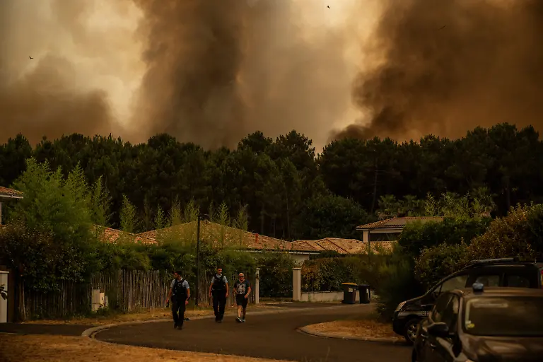 French-Gendarmes-evacuate-a-resident-from-a-residential-area-during-a-wildfire-near-Lege-Cap-Ferret-southwestern-France-on-July-23-2026-The-fire-raging-in-the-northern-part-of-the-Arcachon-Basin-in-Gironde-southwest-France-has-swept-through-more-than-3-400-hectares-according-to-the-latest-figures-released-by-the-prefecture-More-than-20-000-residents-and-tourists-have-been-evacuated-from-this-part-already-devastated-by-flames-in-2022-France-has-been-battered-by-three-heatwaves-since-May-as-part-of-increasingly-common-extreme-weather-episodes-linked-to-climate-change-causing-excess-deaths-drying-up-rivers-and-fuelling-wildfires-Scientists-have-long-warned-that-climate-change-caused-by-human-use-of-fossil-fuels-will-make-periods-of-drought-more-intense-and-longer-lasting-creating-the-ideal-conditions-for-wildfires