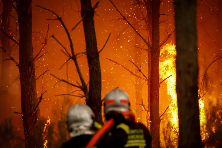 Firefighters-battle-a-forest-fire-in-Saint-Jean-d-Illac-some-30km-from-Bordeaux-on-July-26-2026-as-a-wildfire-has-been-ravaging-the-forest-north-of-the-Arcachon-Basin-Gironde-The-220-000-people-evacuated-due-to-the-massive-wildfire-in-France-s-Gironde-region-will-not-be-able-to-return-home-until-the-fire-has-been-brought-under-control-the-local-prefect-said-also-ruling-out-any-normal-workday-on-Monday-in-the-affected-towns-ahead-of-a-possible-worsening-of-the-situation-on-Tuesday-due-to-an-expected-rise-in-temperatures