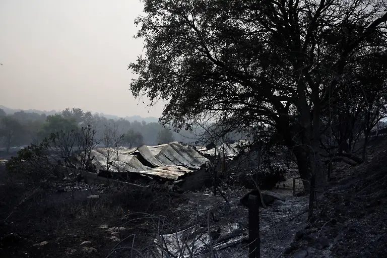 This-picture-shows-the-ruins-of-a-burnt-out-warehouse-following-a-wildfire-in-Casavieja-100-kilometers-south-west-of-Madrid-on-July-27-2026-Spain-faces-two-crucial-days-to-bring-raging-wildfires-under-control-before-weather-conditions-worsen-authorities-said-on-July-27-2026-though-they-were-making-some-progress-and-planned-to-start-returning-evacuees-to-certain-areas-The-wildfires-that-broke-out-in-forested-areas-around-the-Spanish-capital-at-the-height-of-the-summer-holidays-have-forced-some-60-000-people-to-flee-their-homes-often-with-just-minutes-notice-leaving-pets-and-medicine-behind