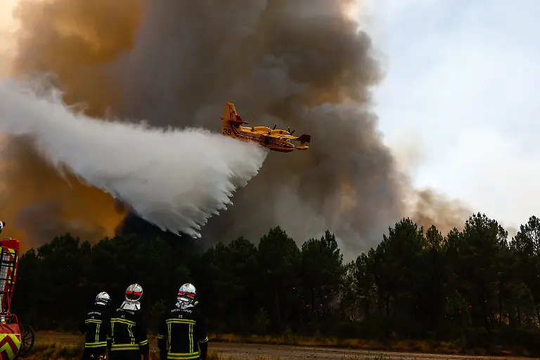 MARTIGNAS-SUR-JALLE-France-July-28-2026-A-major-wildfire-advances-into-the-military-camp-of-Souge-home-to-the-French-Army-s-13th-Parachute-Dragoon-Regiment-13e-Regiment-de-Dragons-Parachutistes-a-special-forces-airborne-intelligence-unit-near-Bordeaux-southwestern-France-Special-forces-commandos-assist-firefighters-by-supplying-water-to-crews-battling-the-fast-moving-blaze-while-Canadair-water-bombers-and-a-Dash-aerial-tanker-conduct-continuous-firefighting-operations-overhead-Ground-assault-teams-work-to-contain-the-fire-as-it-spreads-through-forested-areas-surrounding-the-military-installation-The-wildfire-in-Gironde-mobilized-military-personnel-alongside-civilian-emergency-services-as-aerial-and-ground-firefighting-operations-intensified-to-protect-the-Camp-de-Souge-and-nearby-communities-BENLEULMIELIASNEIL-sipa