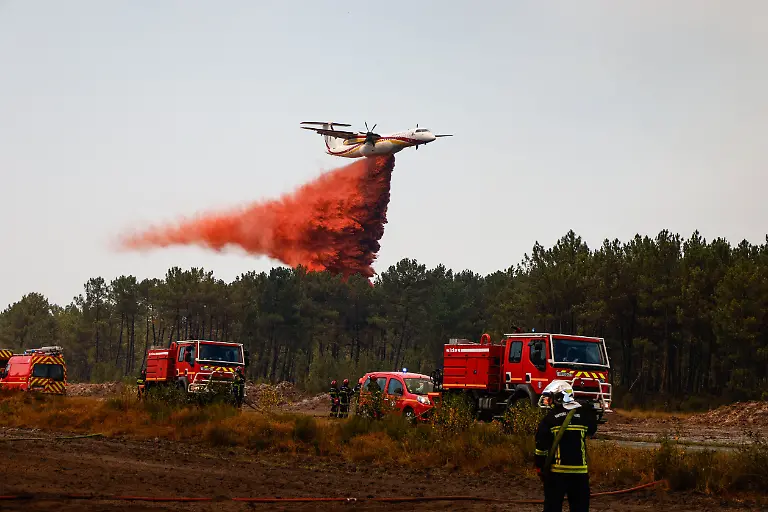 MARTIGNAS-SUR-JALLE-France-July-28-2026-A-major-wildfire-advances-into-the-military-camp-of-Souge-home-to-the-French-Army-s-13th-Parachute-Dragoon-Regiment-13e-Regiment-de-Dragons-Parachutistes-a-special-forces-airborne-intelligence-unit-near-Bordeaux-southwestern-France-Special-forces-commandos-assist-firefighters-by-supplying-water-to-crews-battling-the-fast-moving-blaze-while-Canadair-water-bombers-and-a-Dash-aerial-tanker-conduct-continuous-firefighting-operations-overhead-Ground-assault-teams-work-to-contain-the-fire-as-it-spreads-through-forested-areas-surrounding-the-military-installation-The-wildfire-in-Gironde-mobilized-military-personnel-alongside-civilian-emergency-services-as-aerial-and-ground-firefighting-operations-intensified-to-protect-the-Camp-de-Souge-and-nearby-communities-BENLEULMIELIASNEIL-sipa