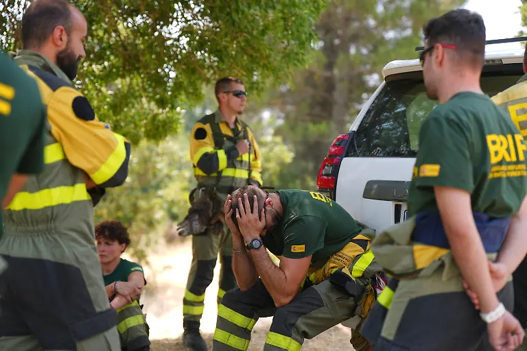 Aesir-Diaz-M-Techniker-bei-den-spanischen-Waldbrand-Einsatzbrigaden-BRIF-sitzt-waehrend-einer-Pause-bei-der-Bekaempfung-eines-Waldbrands-in-Sotillo-de-Adrada-neben-seinen-Teamkollegen-waehrend-sich-das-Feuer-weiter-ausbreitet