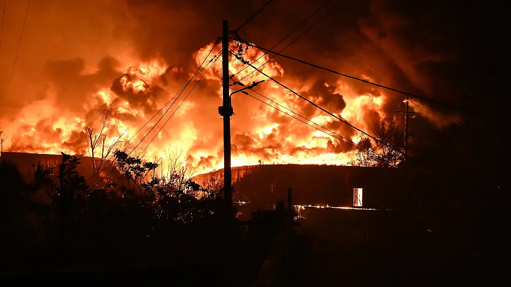 Bei-einem-Waldbrand-am-Rande-der-nordgriechischen-Stadt-Thessaloniki-steigen-Flammen-aus-einem-brennenden-Gebaeude-auf
