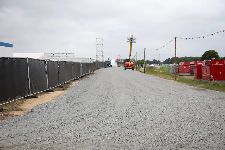 Fahrzeuge-sind-auf-einem-neuen-und-geschotterten-Rettungsweg-zwischen-Veranstaltungsgelaende-und-Campingflaechen-bei-einem-Medientermin-auf-dem-Festivalgelaende-des-Wacken-Open-Airs-WOA-unterwegs-Das-Wacken-Open-Air-WOA-vom-29-Juli-bis-zum-1-August-gilt-als-groesstes-Heavy-Metal-Festival-der-Welt-zu-dpa-Das-kleine-Wacken-bereitet-sich-auf-85