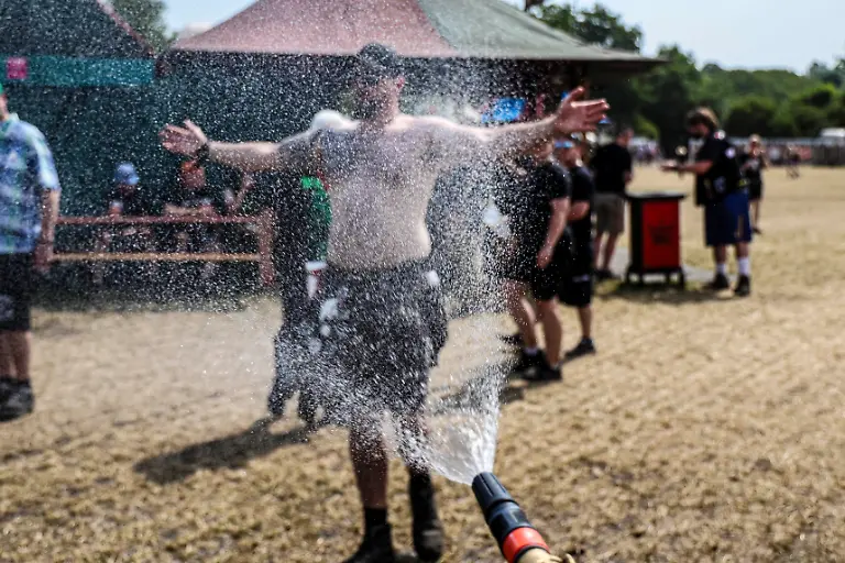 Ein-Mann-goennt-sich-eine-Erfrischung-vor-einem-Gartenschlauch-beim-Wacken-Open-Air-W-O-A-Das-W-O-A-gilt-als-groesstes-Heavy-Metal-Festival-der-Welt
