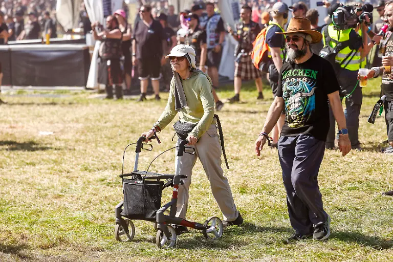 Ein-Mann-und-eine-Frau-gehen-waehrend-der-Eroeffnung-auf-ueber-das-Infield-beim-Wacken-Open-Air-W-O-A-Das-W-O-A-gilt-als-groesstes-Heavy-Metal-Festival-der-Welt