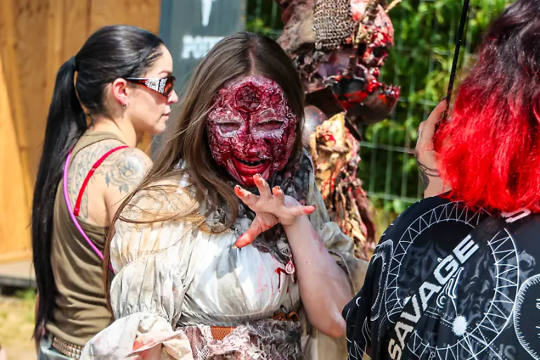 Eine-als-Zombie-verkleidete-Darstellerin-geht-ueber-das-Gelaende-beim-Wacken-Open-Air-W-O-A-Das-W-O-A-gilt-als-groesstes-Heavy-Metal-Festival-der-Welt