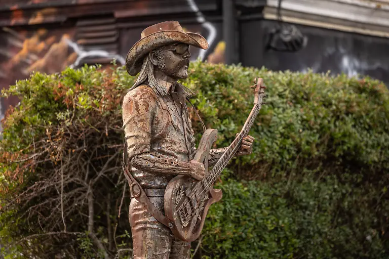 Das-Dorf-Wacken-fuellt-sich-bereits-am-Montag-wieder-mit-Fans-aus-aller-Welt-Lemmy-Kilmisters-Statue-am-Langasthof-beobachtet-die-Szene-Das-Wetter-hat-sich-puenktlich-zum-Montag-gebebessert-Zeit-fuer-die-angereisten-Metalheads-in-das-beruehmte-Dorf-Wacken-zu-gehen-um-sich-mit-Getraenken-und-T-Shirts-einzudecken-Wacken-Wacken-open-Air-Schleswig-Holstein-Deutschland-5DL7405-The-village-of-Wacken-is-already-filling-up-again-on-Monday-with-fans-from-all-over-the-world-Lemmy-Kilmisters-statue-at-the-Langasthof-watches-over-the-scene-The-weather-has-improved-just-in-time-for-Mondaytime-for-the-metalheads-whove-traveled-here-to-head-into-the-famous-village-of-Wacken-to-stock-up-on-drinks-and-T-shirts