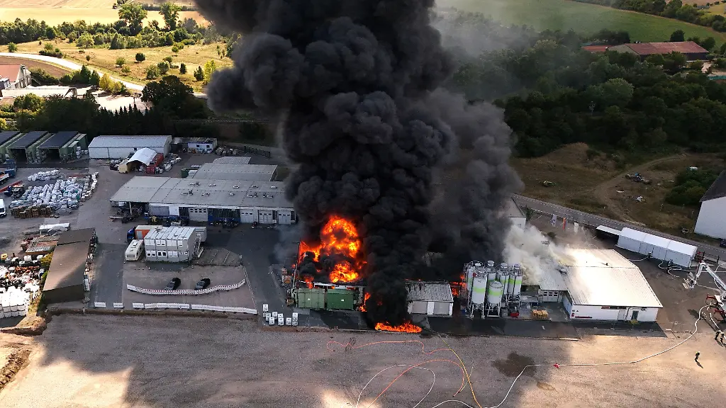 Flammen-und-dichter-Rauch-steigen-aus-den-Gebaeuden-eines-Kunststoffbetriebs-Mehrere-angrenzende-Wohnhaeuser-wurden-geraeumt-mehrere-Bewohnerinnen-und-Bewohner-werden-von-Einsatzkraeften-betreut-wie-der-Landkreis-Mainz-Bingen-mitteilte-Die-Bahnstrecke-bei-Sprendlingen-wurde-sicherheitshalber-gesperrt