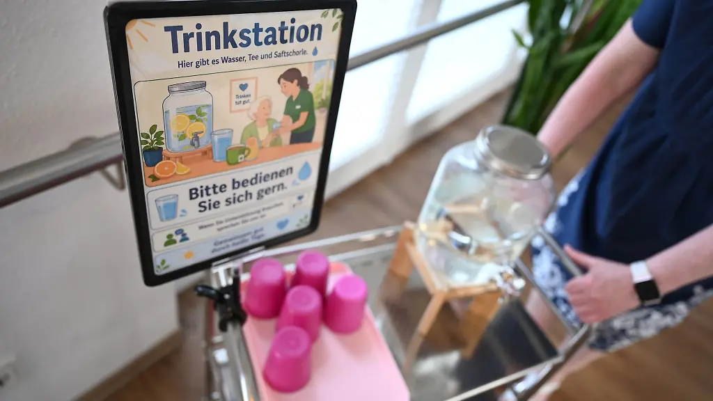 Eine-Frau-schiebt-in-einem-Pflegeheim-einen-Wagen-mit-Trinkbechern-und-Wasser