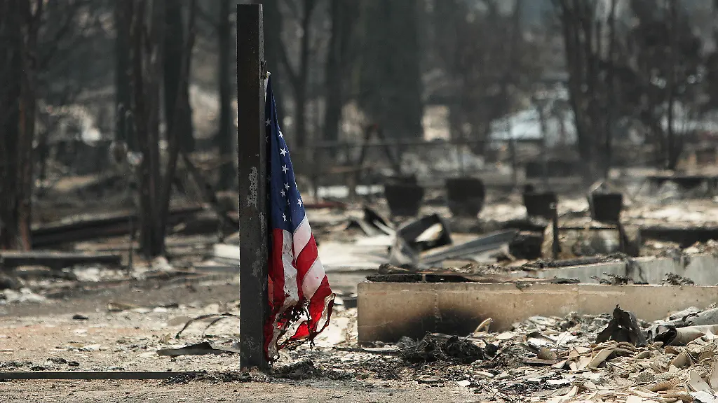 Eine-amerikanische-Flagge-weht-vor-einem-abgebrannten-Gebaeude-in-einem-Wohngebiet-von-Westgate-nach-einem-Waldbrand-in-Spokane-Washington