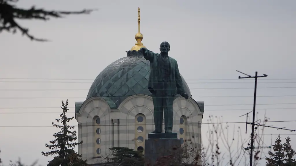 Vom-Stadtzentrum-aus-in-Ufernaehe-ist-auf-einem-Hochplateau-das-markante-Lenin-Denkmal-der-Stadt-zu-sehen-vor-dem-Hintergrund-der-Kuppel-der-zentralen-Kathedrale-Russland-begeht-in-diesem-Jahr-den-10-Jahrestag-der-Annexion-der-voelkerrechtlich-zur-Ukraine-gehoerenden-Krim