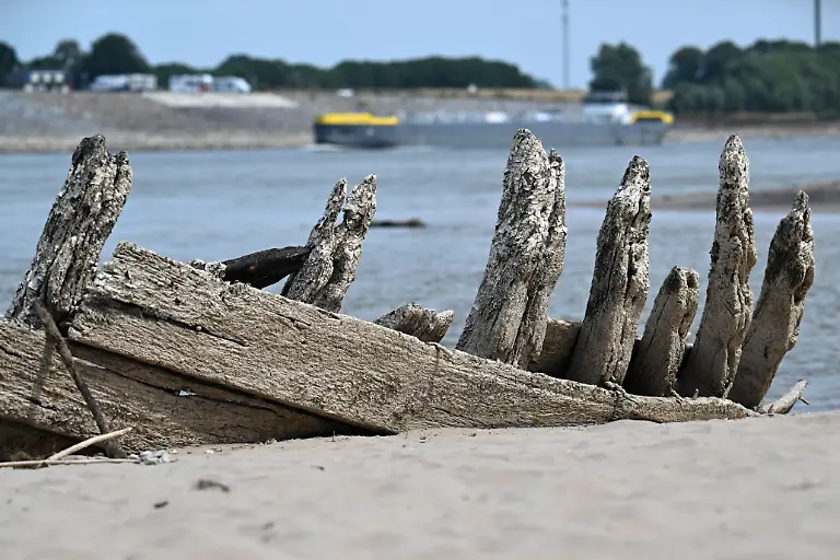 Durch-das-Niedrigwasser-ist-auf-dem-Rhein-das-Wrack-des-einstigen-Holz-Frachtschiffes-De-Hoop-aus-dem-spaeten-19-Jahrhundert-aufgetaucht-1895-hatte-sich-beim-Umladen-von-Dynamit-eine-Explosion-ereignet-bei-der-16-Menschen-starben-und-das-Schiff-zerstoert-wurde-Das-Rekord-Niedrigwasser-des-Rheins-hat-in-Nordrhein-Westfalen-seinen-tiefsten-Stand-wahrscheinlich-bisher-nicht-erreicht-Laut-Prognose-des-Wasserstrassen-und-Schifffahrtsamtes-Rhein-werden-am-06-und-07-August-2026-noch-drastischere-Tiefstaende-fuer-Koeln-Duesseldorf-Duisburg-Ruhrort-und-Emmerich-erwartet