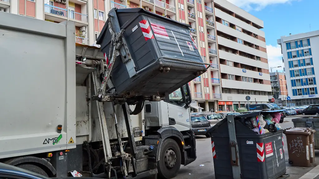 A-garbage-truck-collects-unsorted-urban-waste-The-editorial-image-shows-a-garbage-truck-during-the-automated-emptying-of-a-bin-containing-unsorted-municipal-solid-waste-The-photo-highlights-the-waste-collection-process-in-urban-areas-and-the-importance-of-efficient-waste-management-systems-to-maintain-city-cleanliness-and-environmental-sustainability-in-Bari-Italy-on-October-8-2025