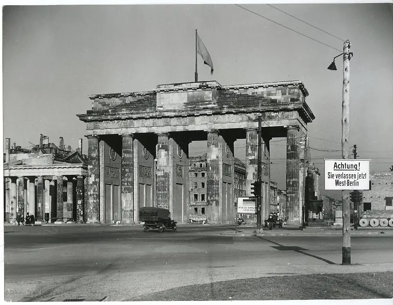 Berlin-Mitte-Kriegsende-Sektorengrenze-West-Berlin-Das-Brandenburger-Tor-zu-Zeiten-vor-dem-Bau-der-Berliner-Mauer-mit-einem-Warnschild-im-Vordergrund-um-1948