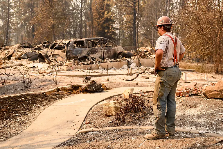 A-utility-worker-views-a-burned-property-during-the-Old-Trails-fire-in-Spokane-Washington-on-August-4-2026-US-authorities-arrested-a-man-on-August-3-2026-on-suspicion-of-arson-in-connection-with-the-biggest-of-three-fires-burning-around-the-northwestern-city-of-Spokane-as-firefighters-raced-to-contain-flames-that-have-displaced-tens-of-thousands-Wildfires-supercharged-by-drought-and-intense-heat-have-torn-through-the-city-in-Washington-state-burning-thousands-of-acres-and-reducing-hundreds-of-buildings-to-cinders-while-anxious-families-await-news-on-when-they-can-return
