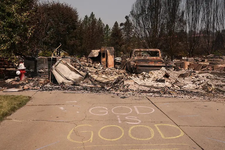 A-God-is-good-sign-is-written-in-chalk-next-to-a-fire-hydrant-and-a-burned-house-after-a-wildfire-hit-the-northwest-part-of-Spokane-Wash-Tuesday-Aug-4-2026
