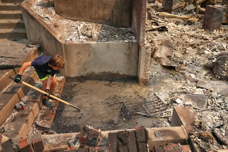 Aaren-Hartley-8-uses-a-shovel-to-sift-through-the-remains-of-his-grandparents-home-after-a-wildfire-hit-the-northern-part-of-Spokane-Wash-Monday-Aug-3-2026